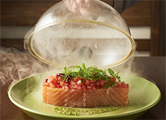 「Bistro CAMPARI(カンパリ)」「カモメ氷菓店」 求人 人気メニューのサーモンコンフィ。ご提供直前に瞬間燻製にして燻製の香りを纏わせる等、美味しさに加えて演出にも驚きを！